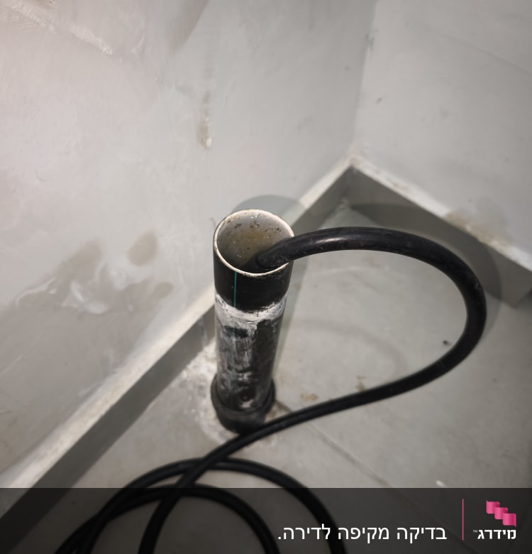 צינור שחור מחובר לקיר עם חיבורי מים